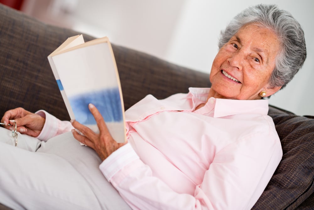 Elder woman reading a book relaxing at home